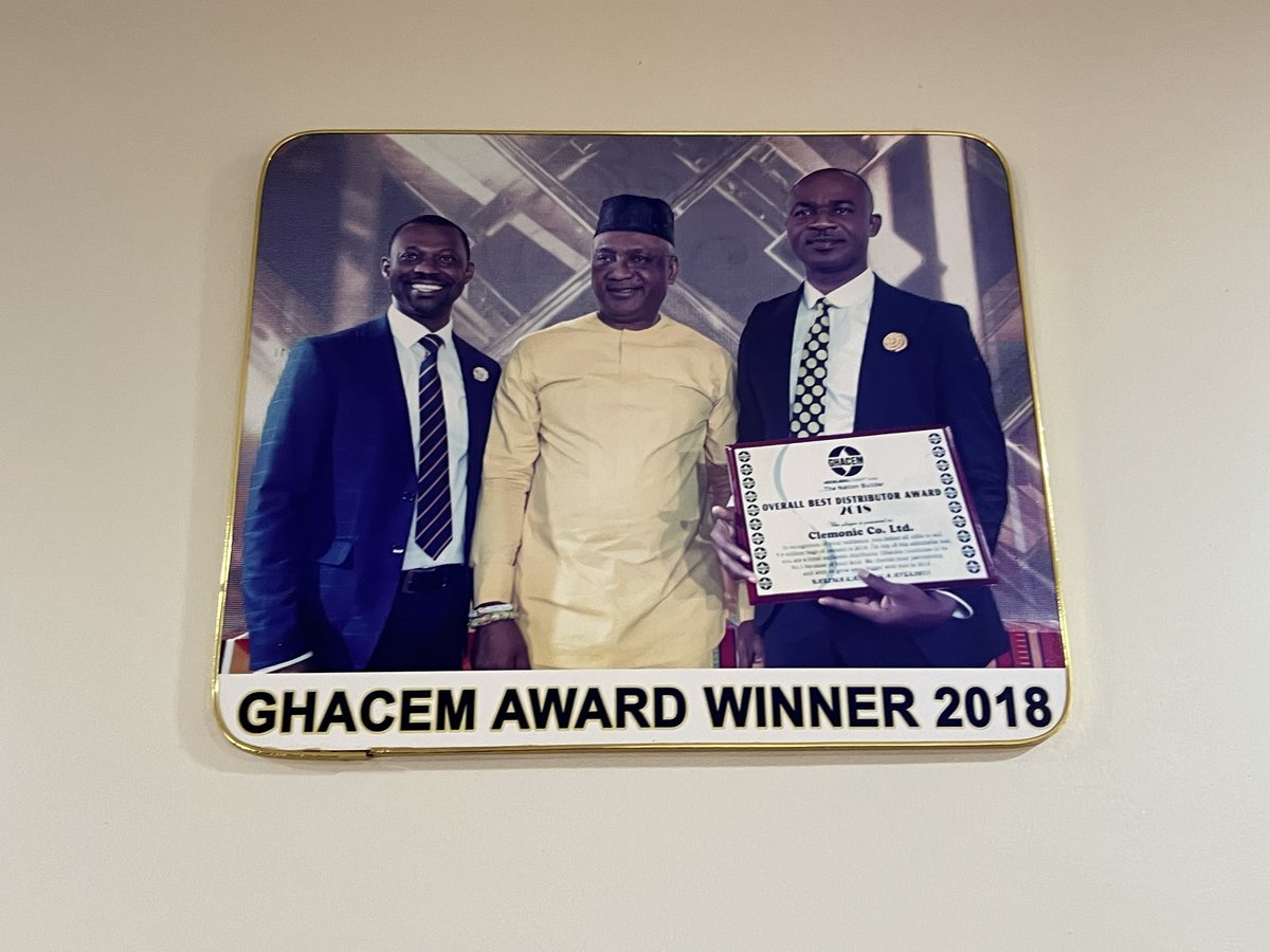 Photo board captioned GHACEM AWARD WINNER 2018: three men on stage at Ghacem's awards night, one holding the Overall Best Distributor Award 2018 plaque presented to Clemonic Co. Ltd.