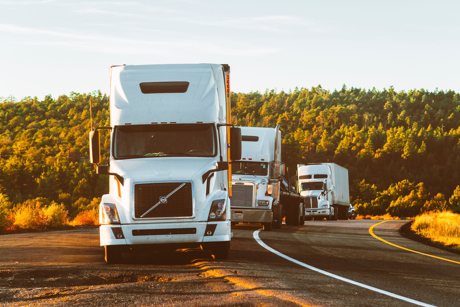 Haulage trucks on the open road at sunset